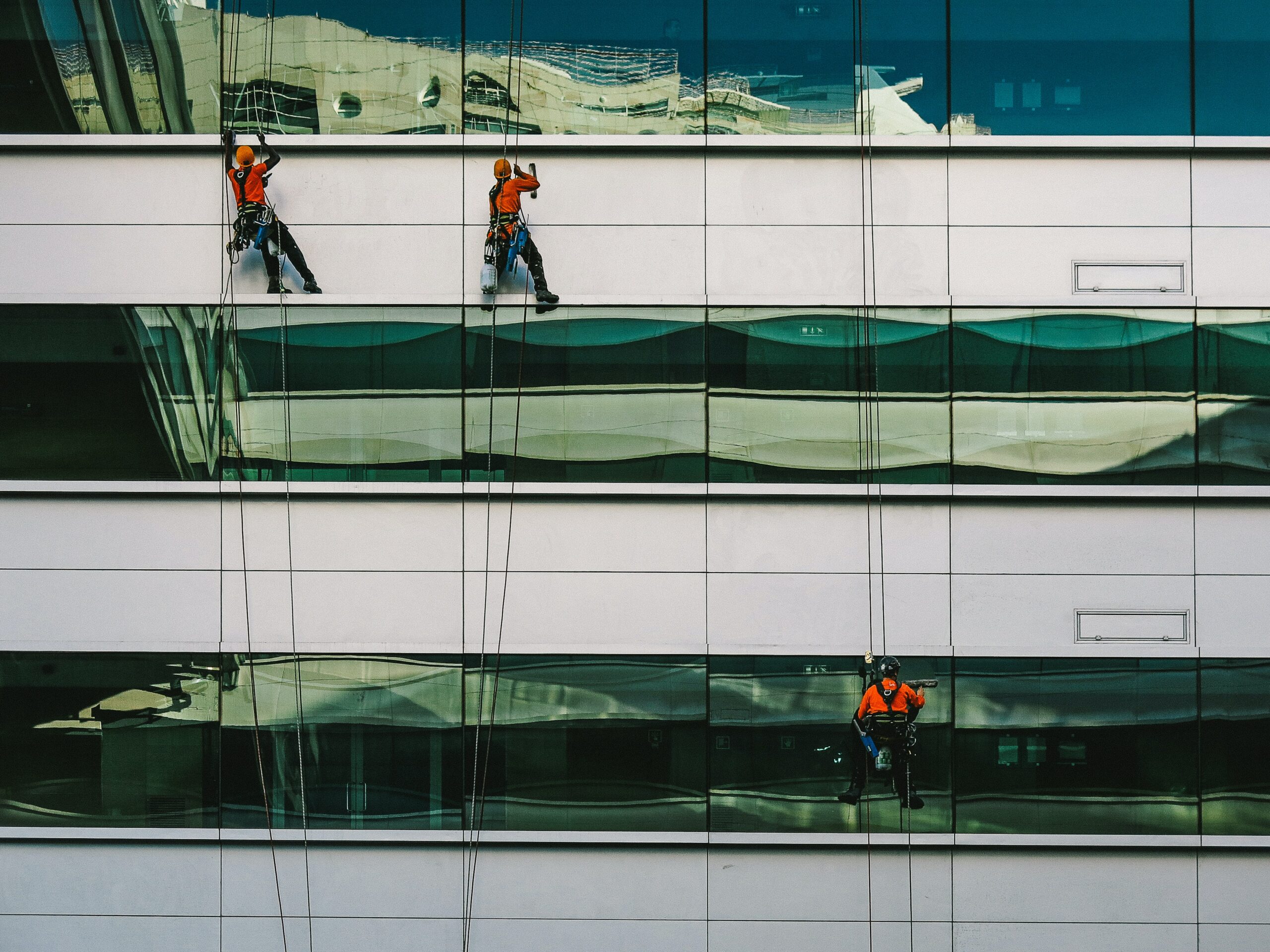 Professional Service workers washing windows on a white building. Two workers are higher than one lower down worker | Unit4 professional services study