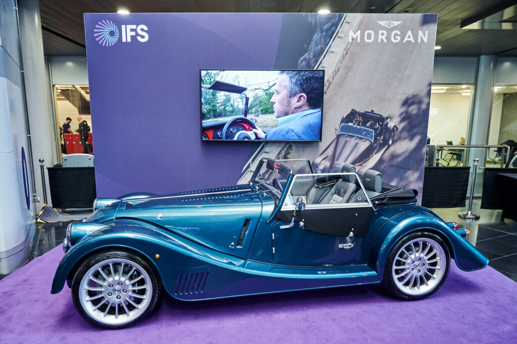image of blue metallic Morgan Motor car in front of IFS Cloud branding | Morgan Motor Company and IFS Cloud