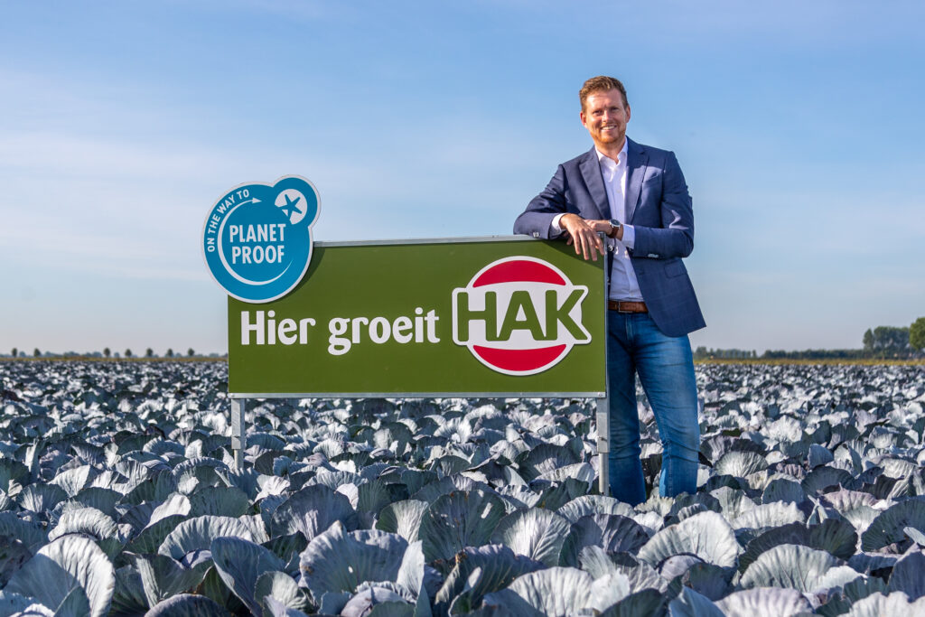 Maikel Jongenelis standing next to a HAK sign with the company logo