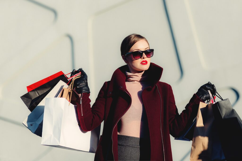 A fashionable lady in large sunglasses walking with hands full of shopping bags | Farm to fashion