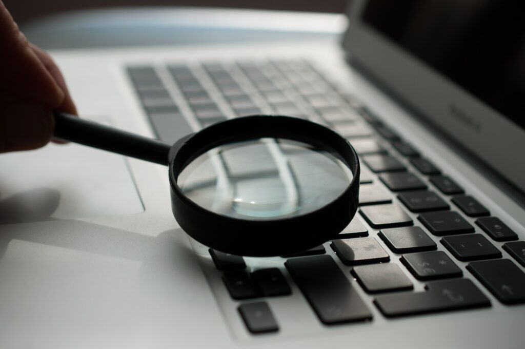 Close up of a magnifying glass being held over the keyboard of a Macbook | Test automation