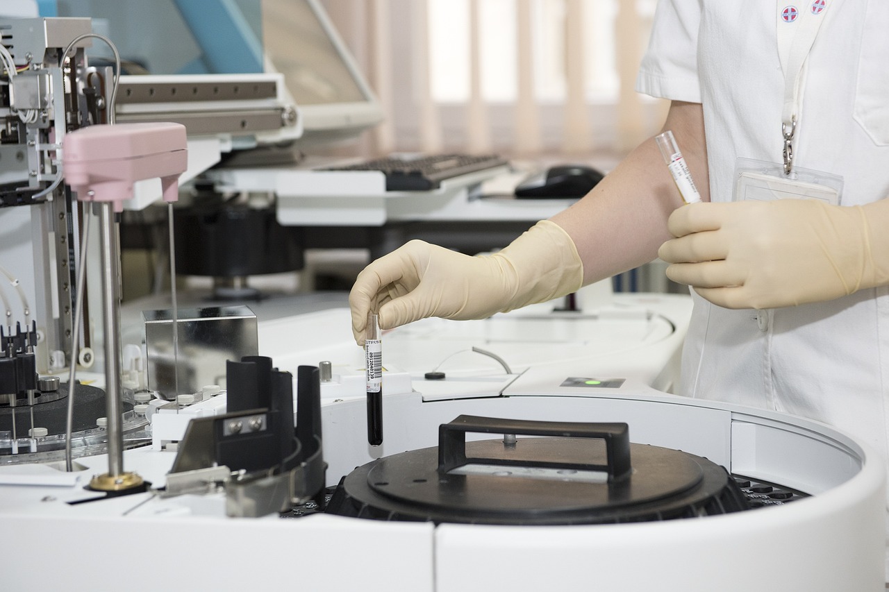 Lab assistant delicately inserts test tube containing a dark substance into a testing machine | Price transparency healthcare