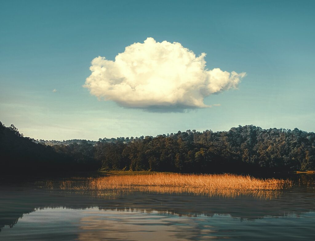 image of one white fluffy cloud with clear blue skies behind over a lake | Inedys and GreenLake