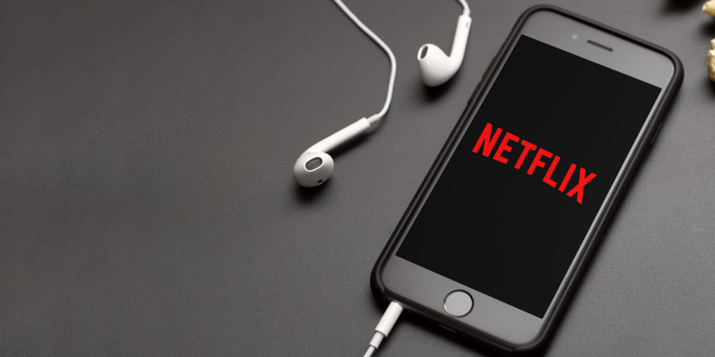 An Iphone with Netflix on screen connected to headphones | SAP and ServiceNow