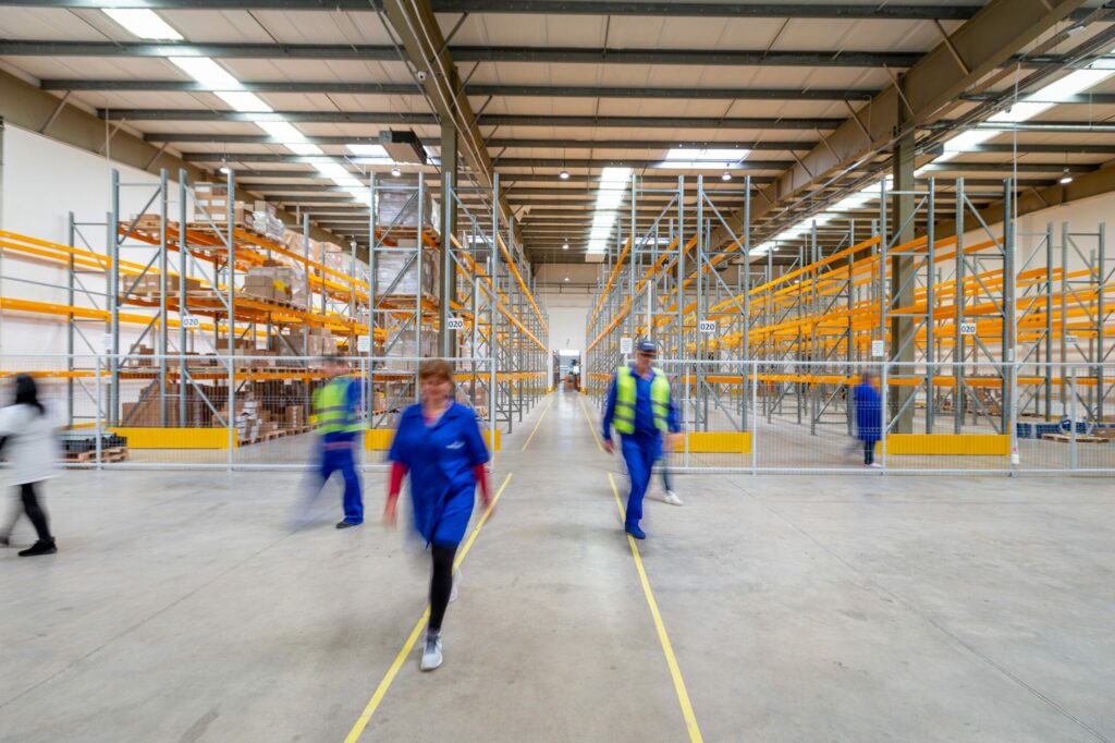 image of warehouse with workers blurred | Infor - democratized data for factory operations