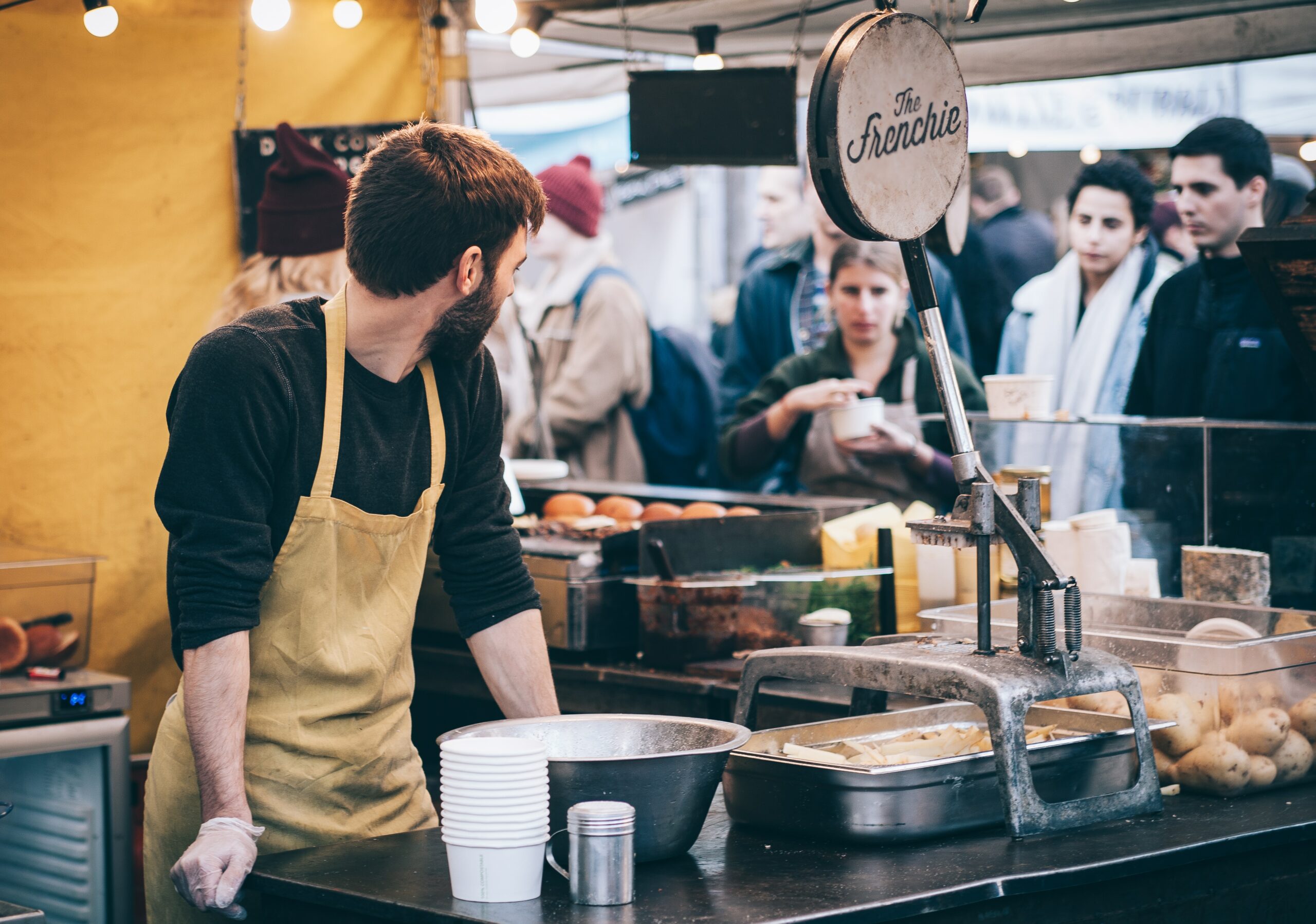 Tired looking chef at a food stall, tending to several, unhappy looking customers | Infor inflation food and beverage