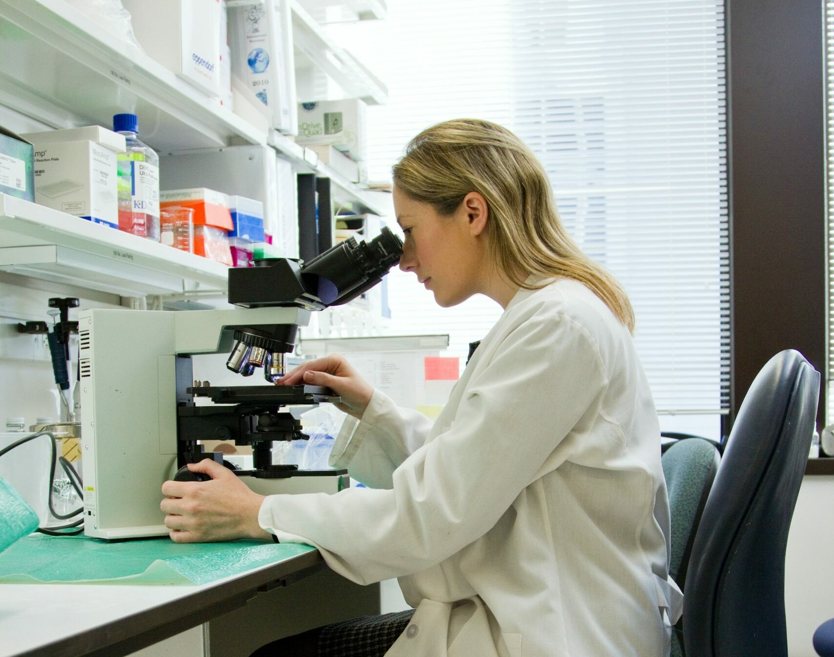 image of person in lab using microscope | Salesforce | Life Sciences Cloud
