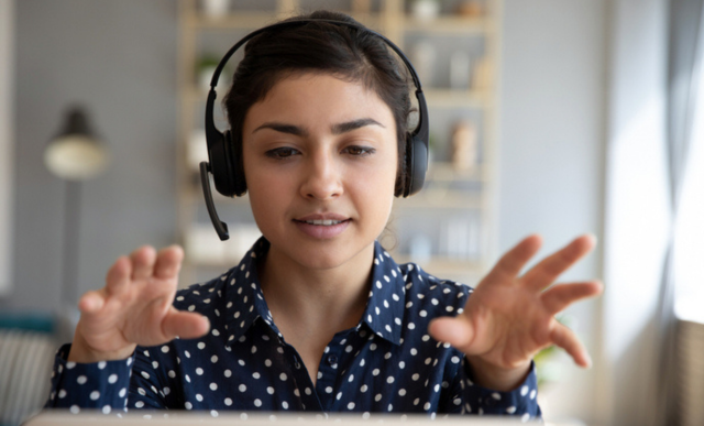 A woman speaks to a laptop with a headset on | Loftware Academies