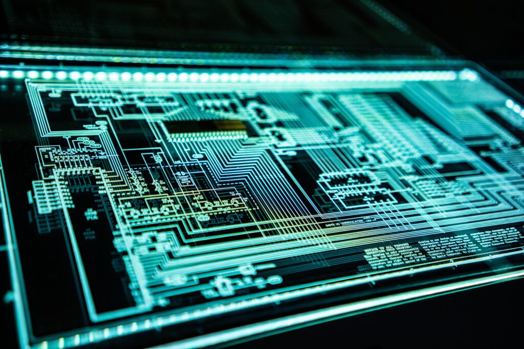Neon-lit circuitboard showing many complex connections against a very dark background | digital transformation Infor