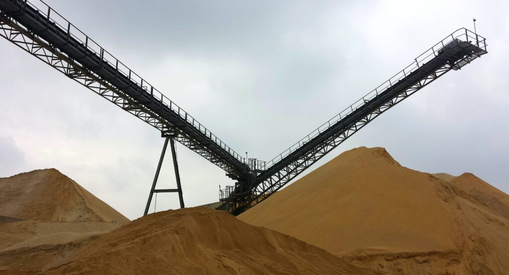 A crane in the middle of several sand dunes, with the dunes being too tall to see the base of the crane | Leonhart Group SAP