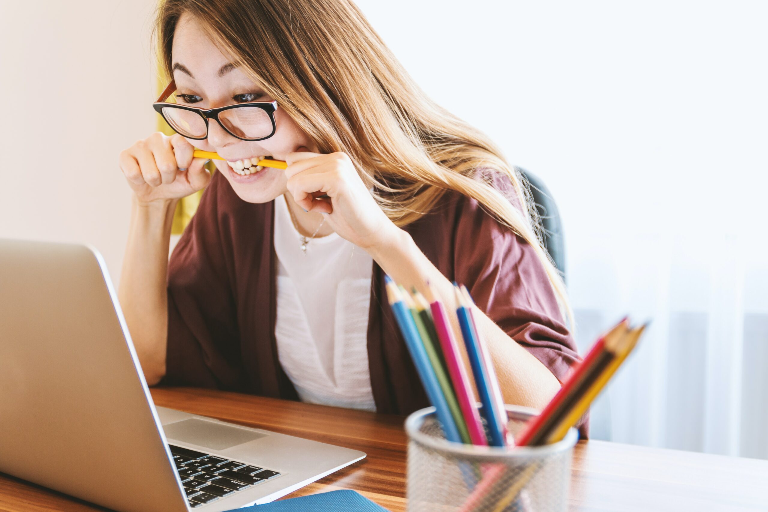 Frustrated and angry looking lady in front of her laptop, chewing on a pencil with rage | SoftwareOne cloud skills gap