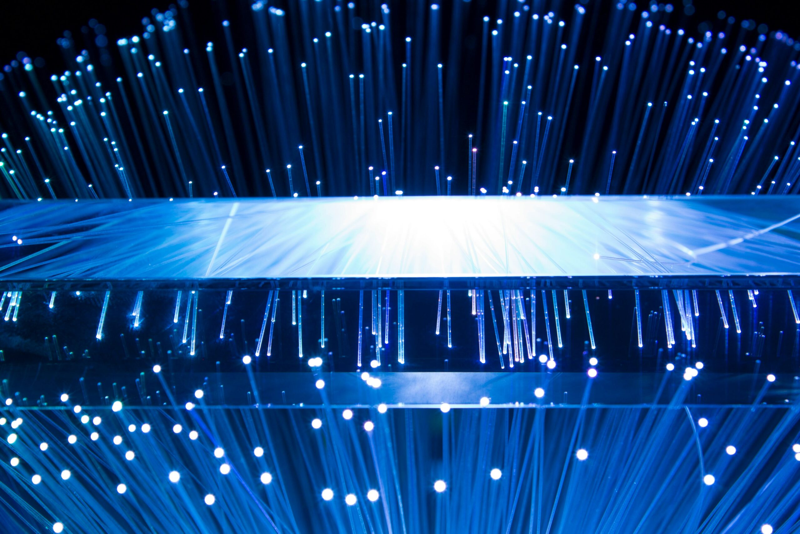 Abstract image of blue fibre lights creeping over the edge of a thin surface | test automation Opkey
