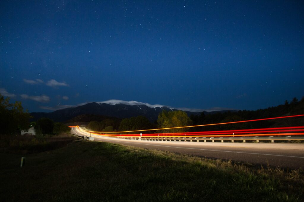 image of long exposure car lights on long road with mountain in the background | Workday and Kainos