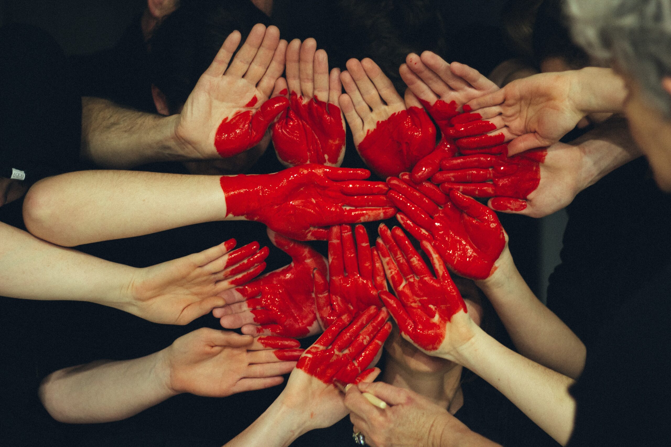 A red heart painted across a large number of outstretched hands | nonprofit Unit4
