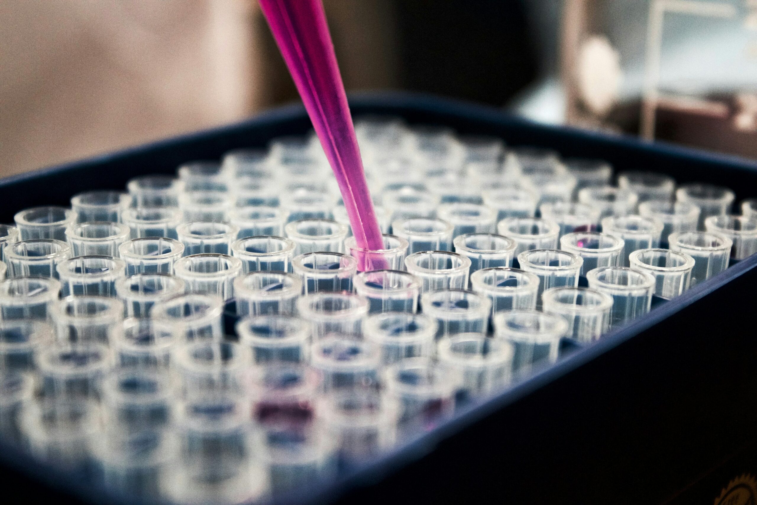 Test tubes currently being injected with a pink pipette | healthcare Infor