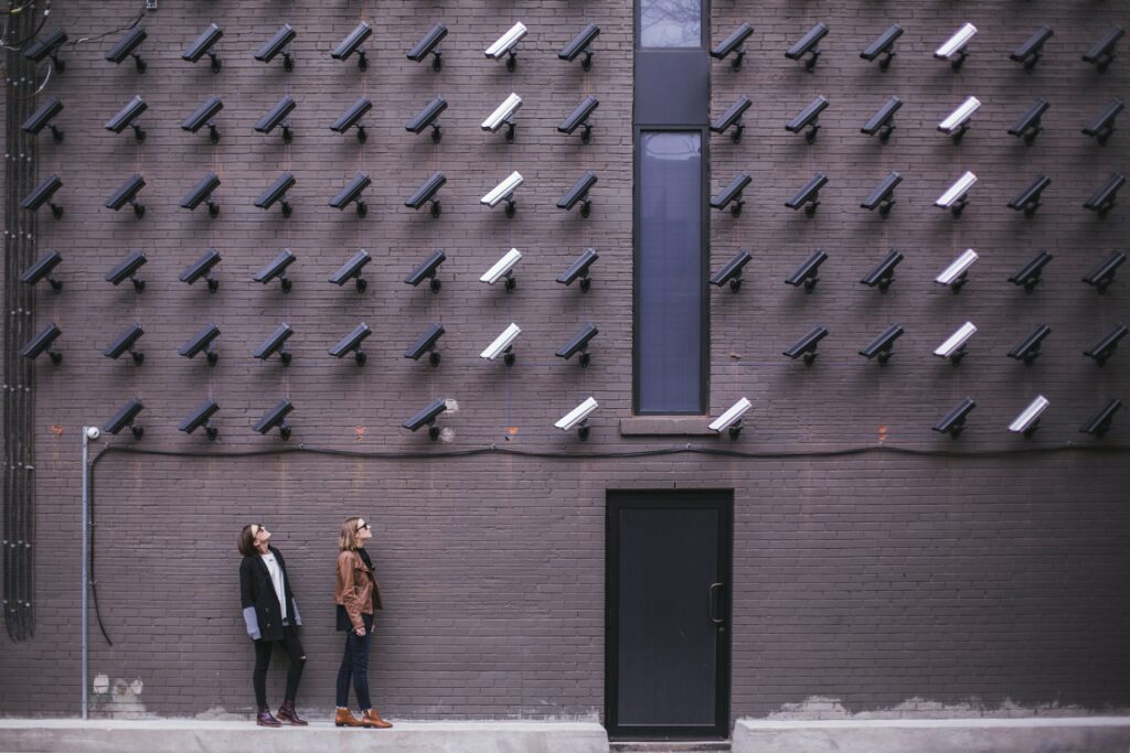 image of people staring at wall of security cameras