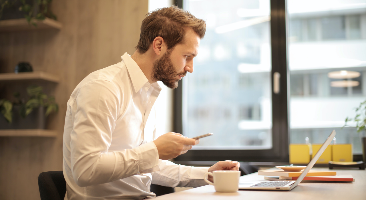 man at desk with laptop and mobile device