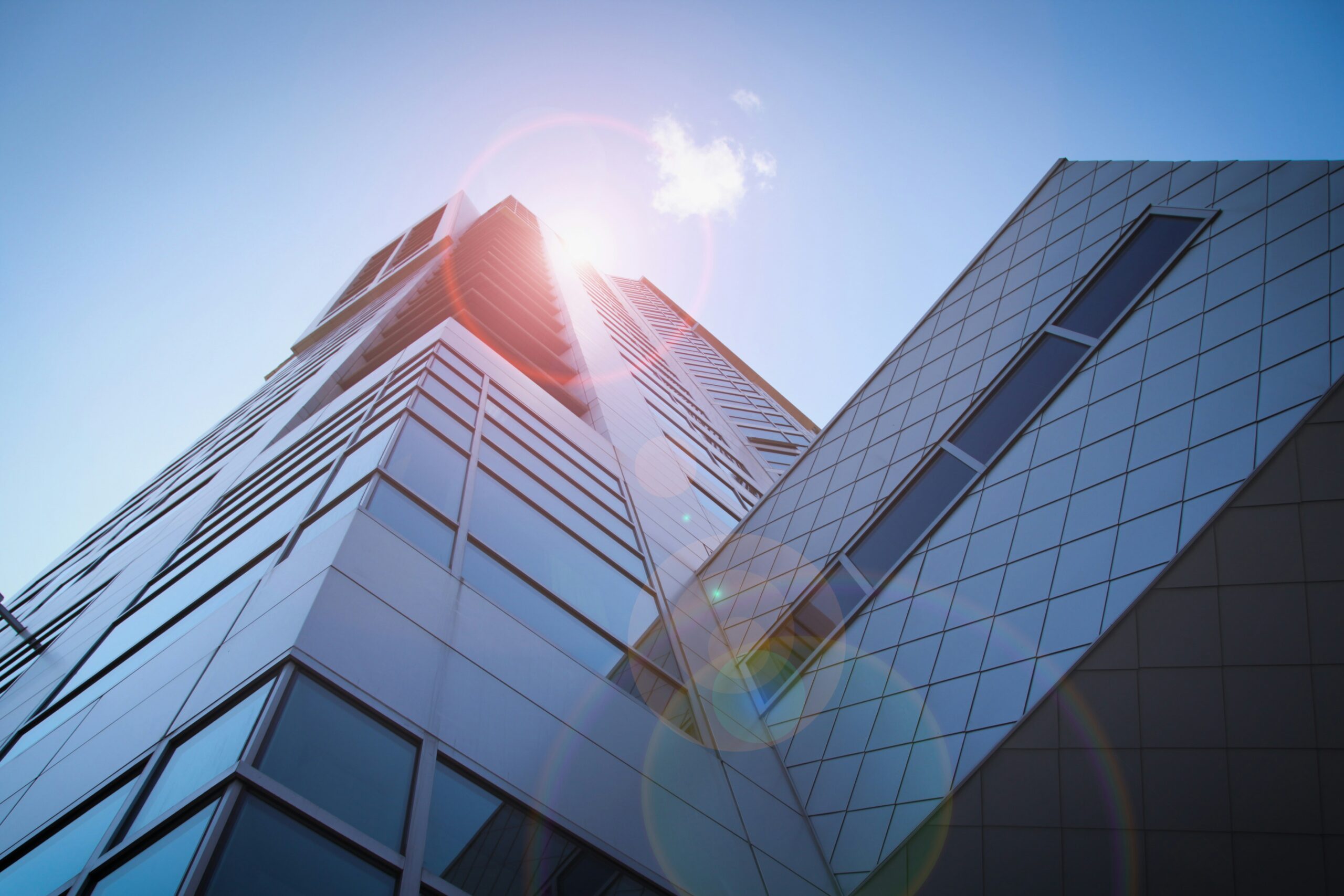 A skyward angle of a tall skyscraper that's reflecting the sunlight into a lens flare | GL Connect SplashBI