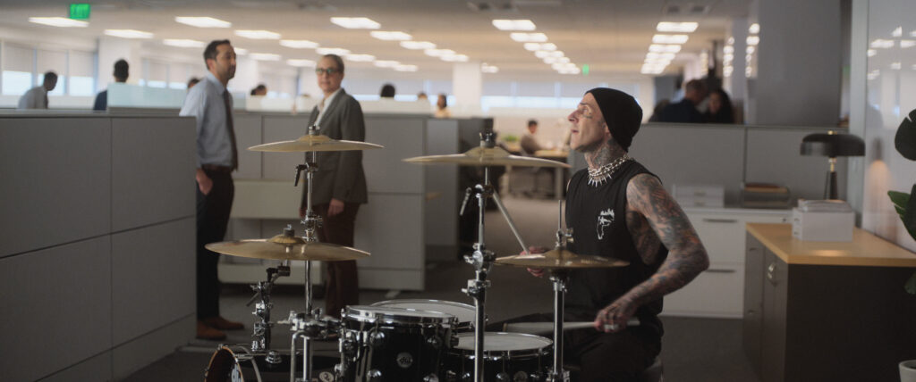 Travis Barker playing drums in a workplace.
