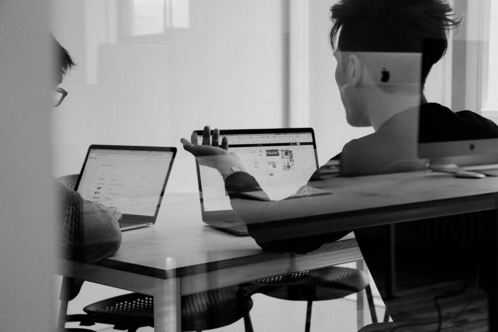 black & white photo of two men using macbooks in an office | financial transformations