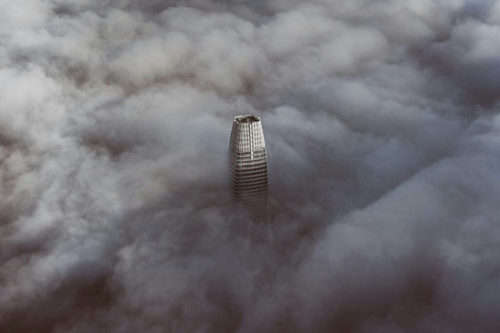 a photograph of a top of Salesforce office building in San Fransisco from a sky view during foggy and cloudy weather