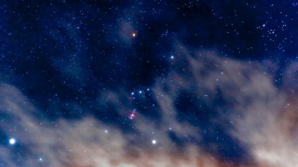 The constellation of Orion shining in a night's sky through light cloud cover | Constellation Shortlist Nextworld