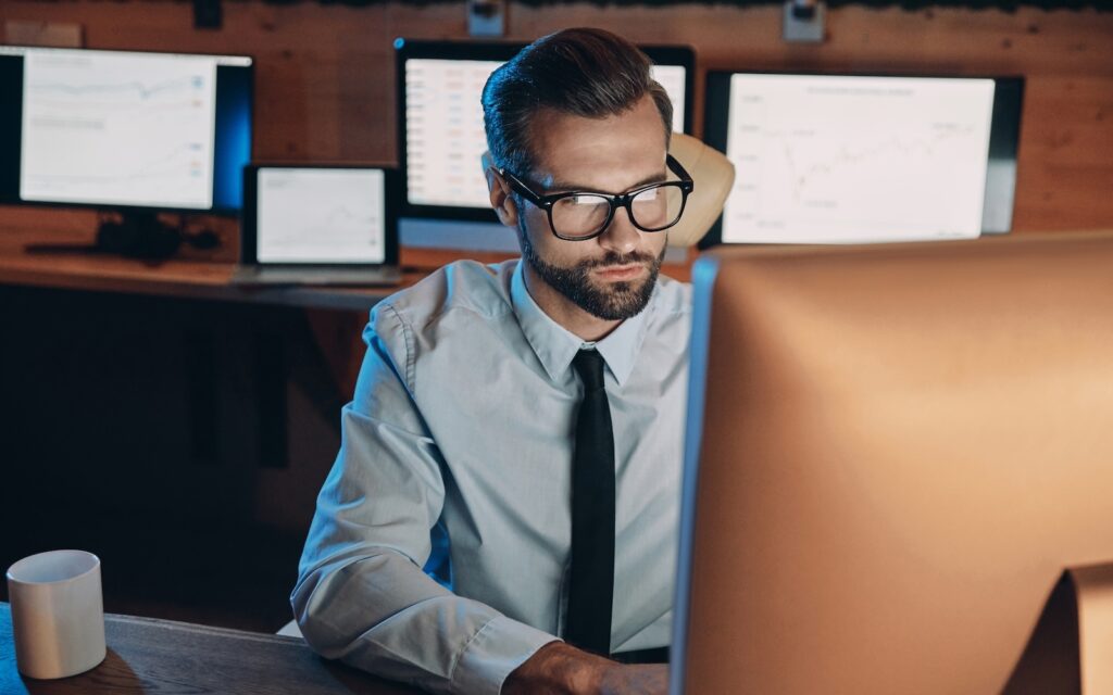 A man sitting in front of computer monitor in an office | Kyriba liquidity network concept