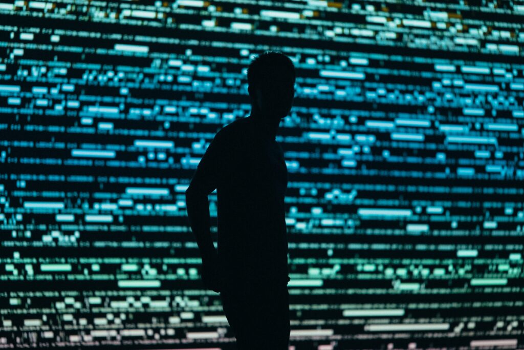 photo of a figure standing in front of blue, green and white-colored screen | market surveillance gen AI solution by Nasdaq and AWS