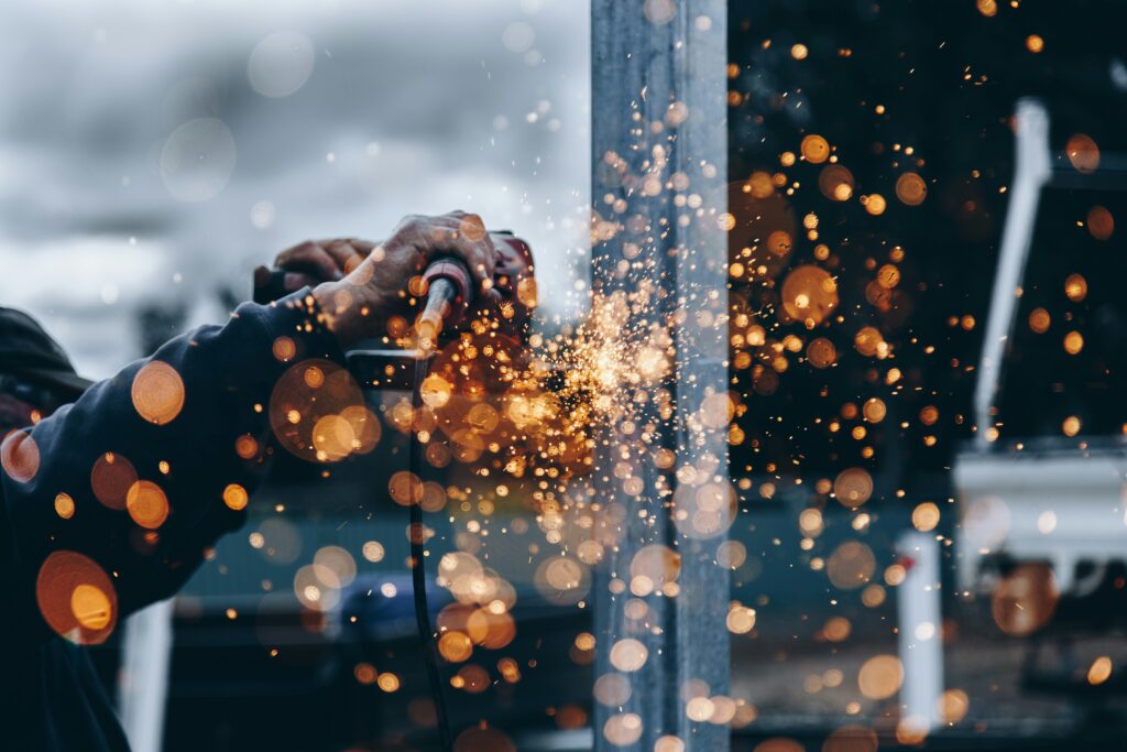 Close up view of a man holding an axel grinder with sparks flying off the metal | manufacturing IFS