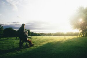 a woman helping an older woman in a wheelchair toward the sun in a field | social worker relief initiatives by Barnsley Council