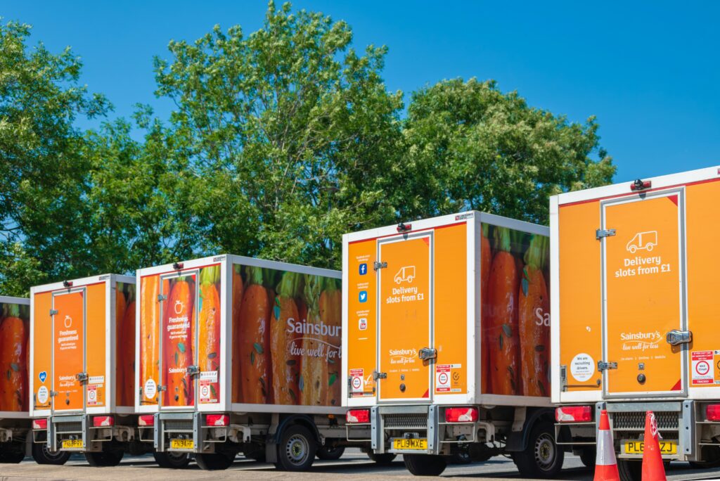 a row of orange Sainsbury's delivery trucks parked next to each other on a sunny day | Microsoft and Sainsbury's AI partnership