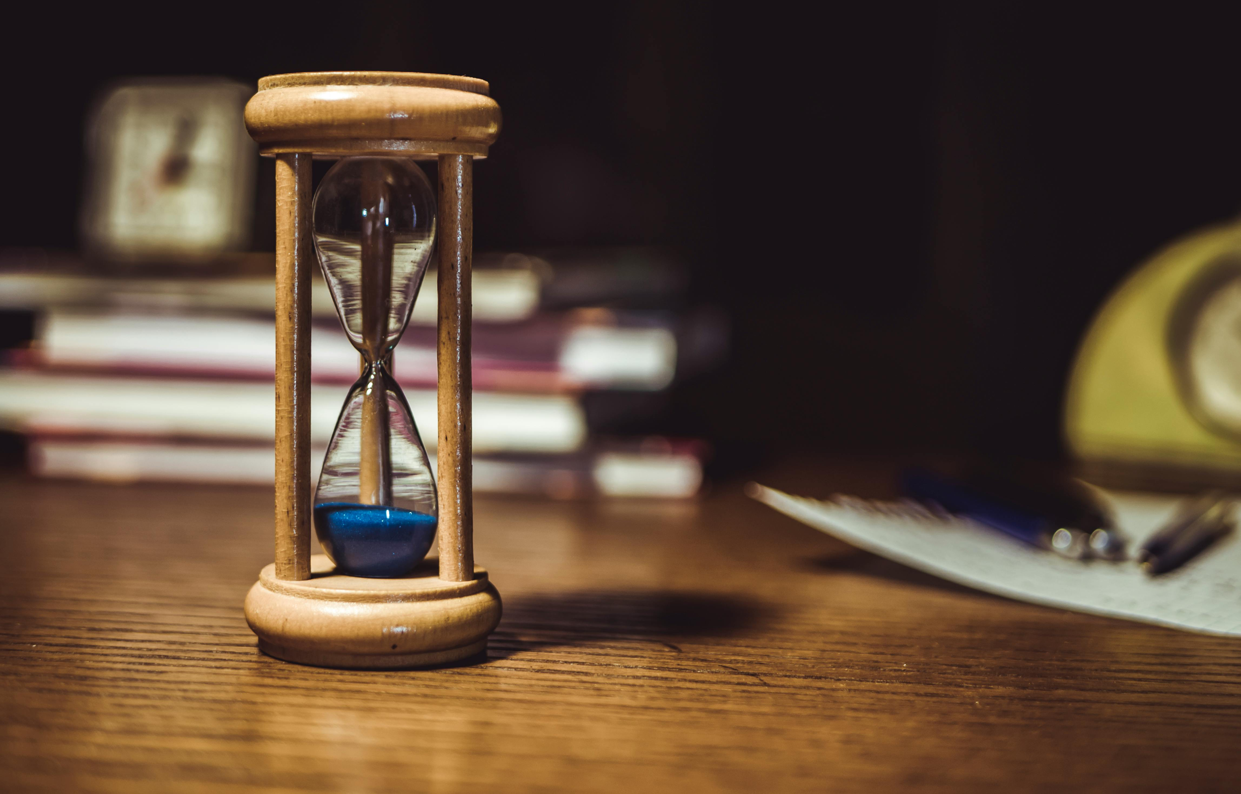 hourglass with blu sand on desk