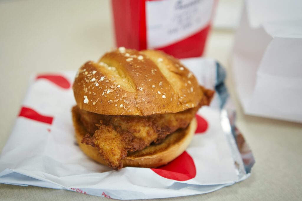 A close up of a chicken burger sitting on top of a chick-fil-a takeout bag | Chick-fil-A SplashBI