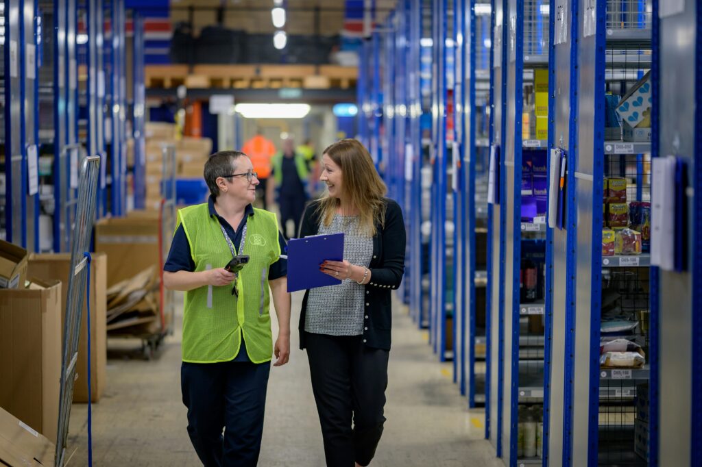 two women walking and smiling in a warehouse | Aptean announces acquisition of Principal Logistics Technologies