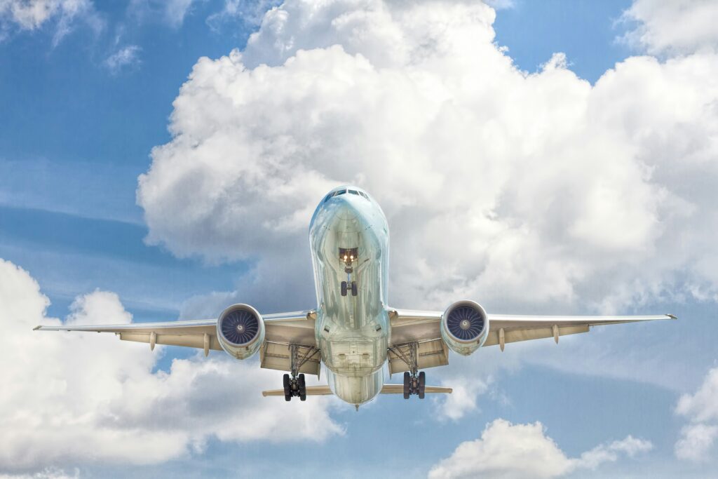 gray and white airplane in the blue sky with clouds | AI solutions for aerospace and defense industry by IFS and EmpoweredMX