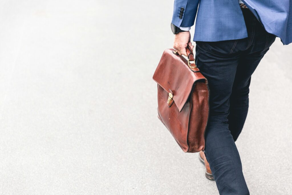 person in formal jacket walking while holding a brown leather bag | HR and Finance solutions from Workday and CloudRock