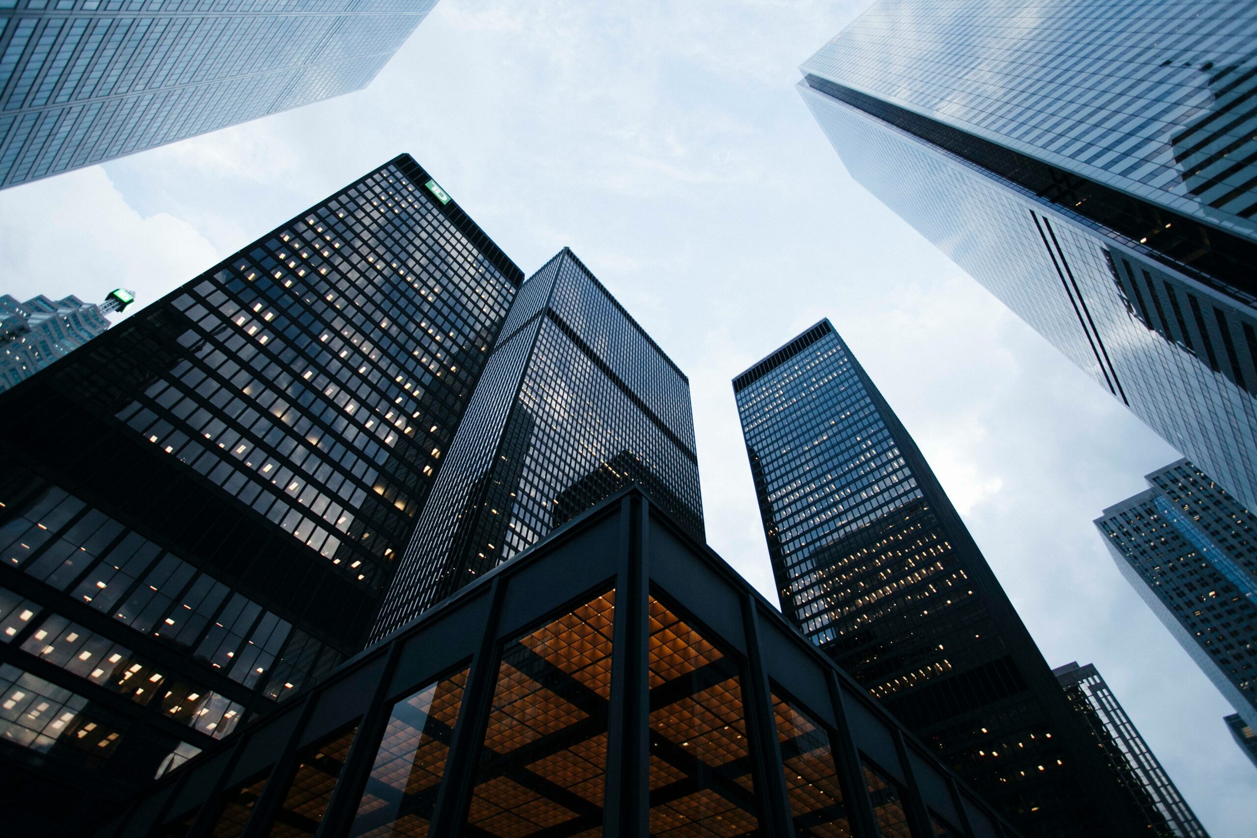 A view of a cityscape from the base of the buildings that shows the dark reflections from the skyscrapers | Copperleaf