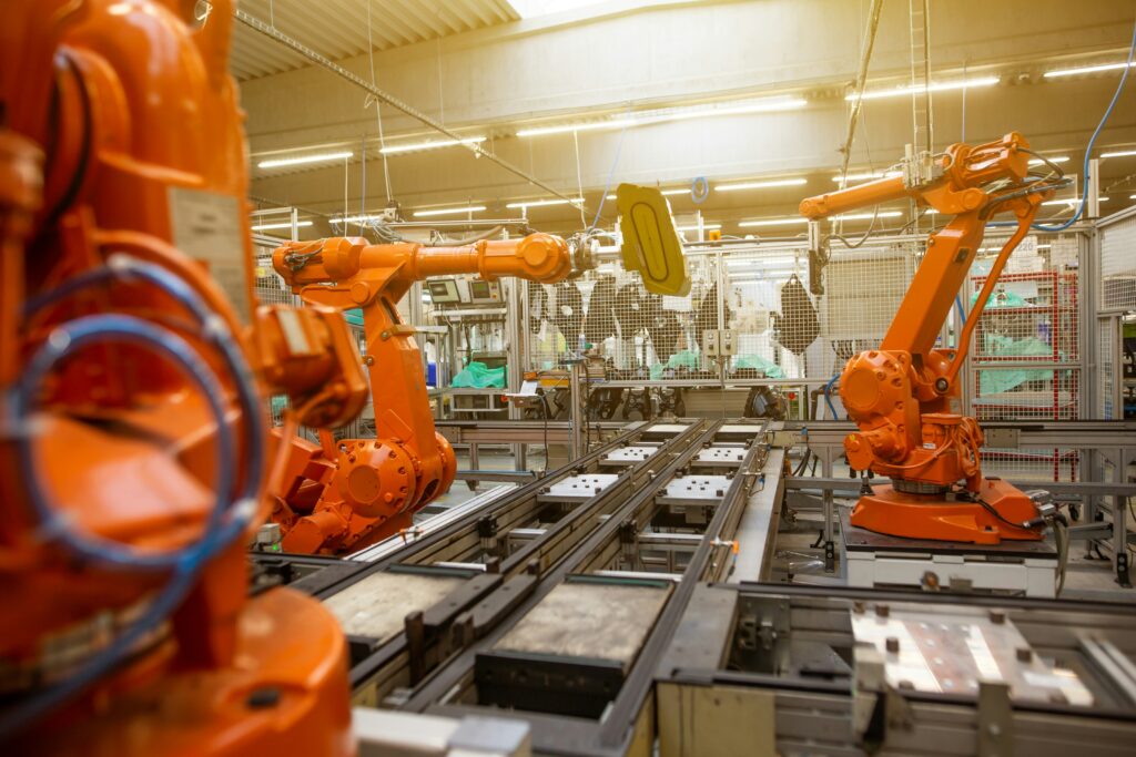 A manufacturing shop floor showing several, orange robot arms ready to start assembling | Global Shop Solutions planning