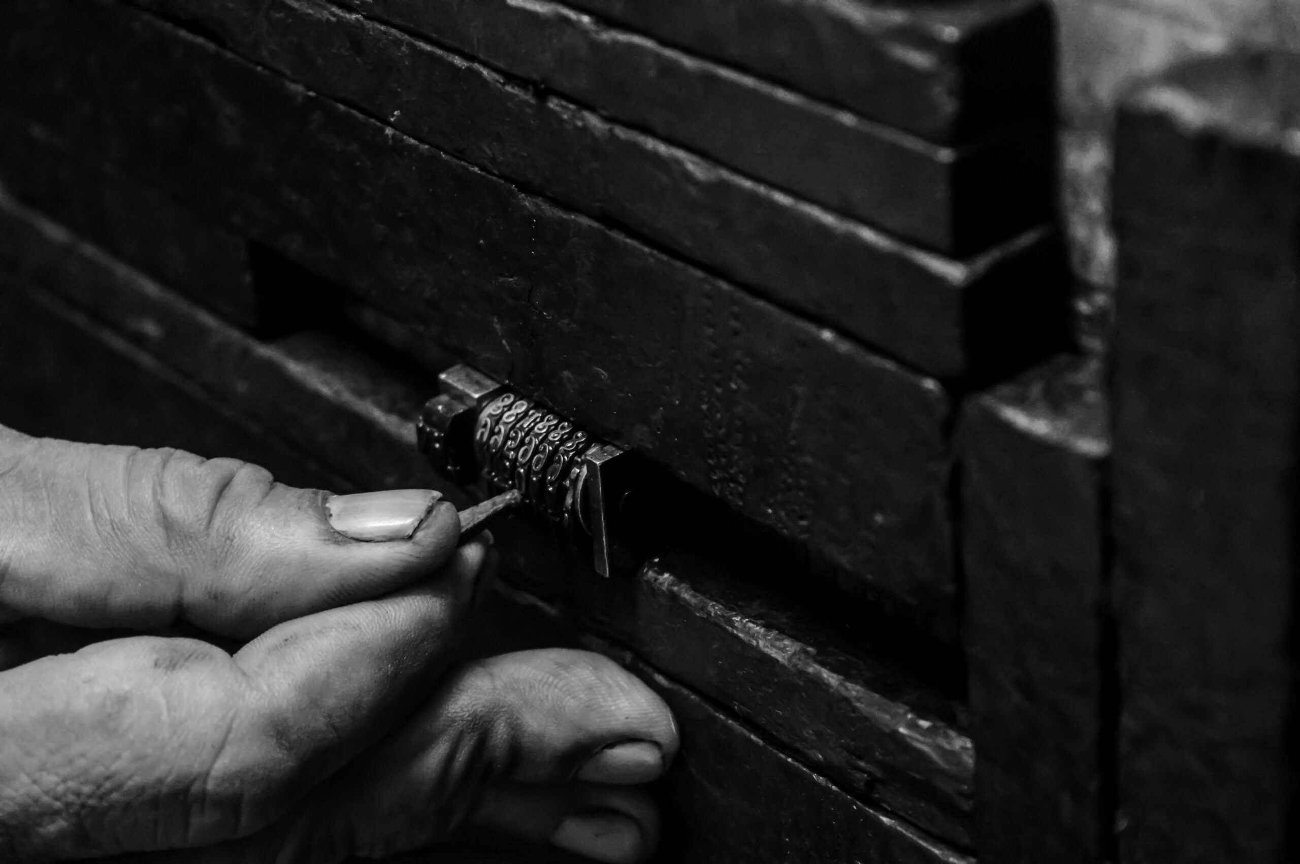 Black and white close up of a hand trying to pick an old combination lock | Delinea internal