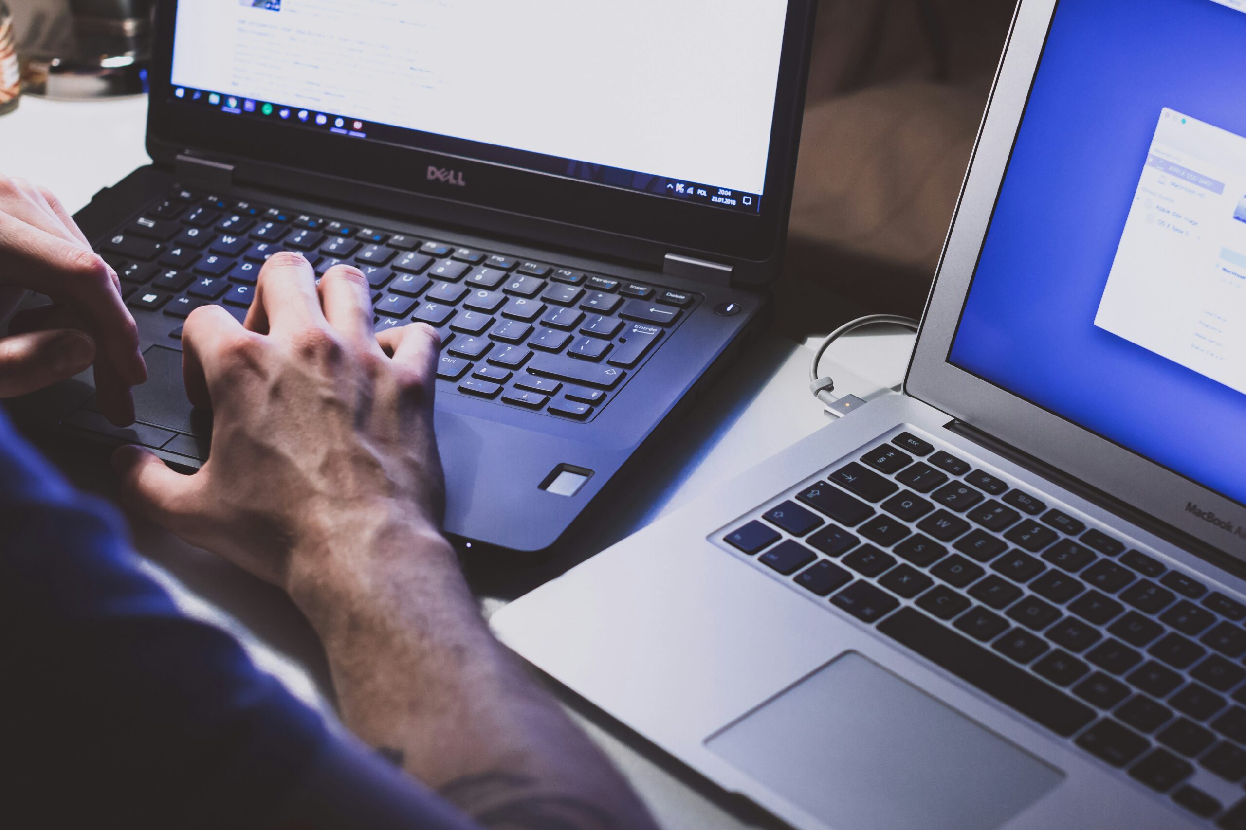 A view of hands working at 2 laptops, one black and one silver | Spinnaker Support ERP transformation