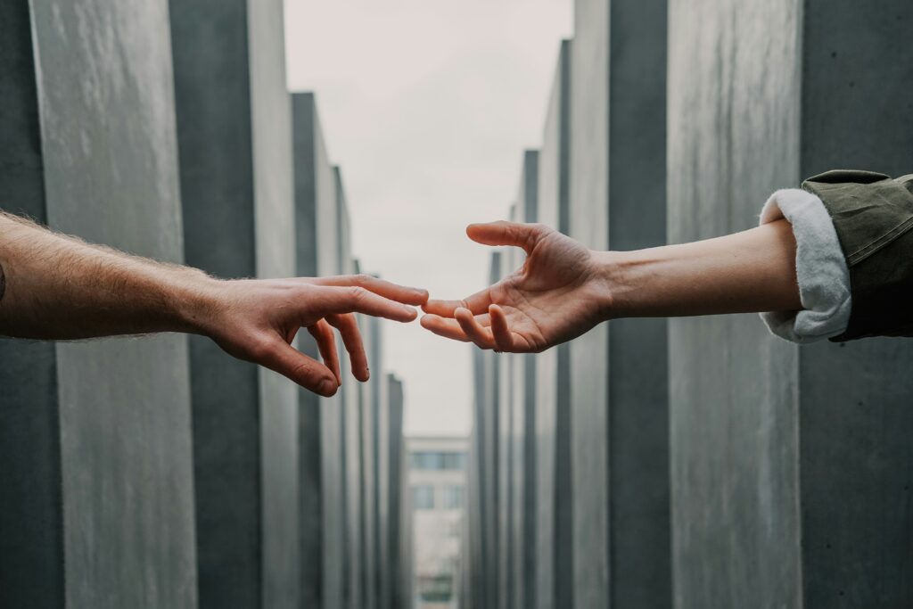 Two human hands reaching out to each other over a bleak and grey landscape | human Rimini Street