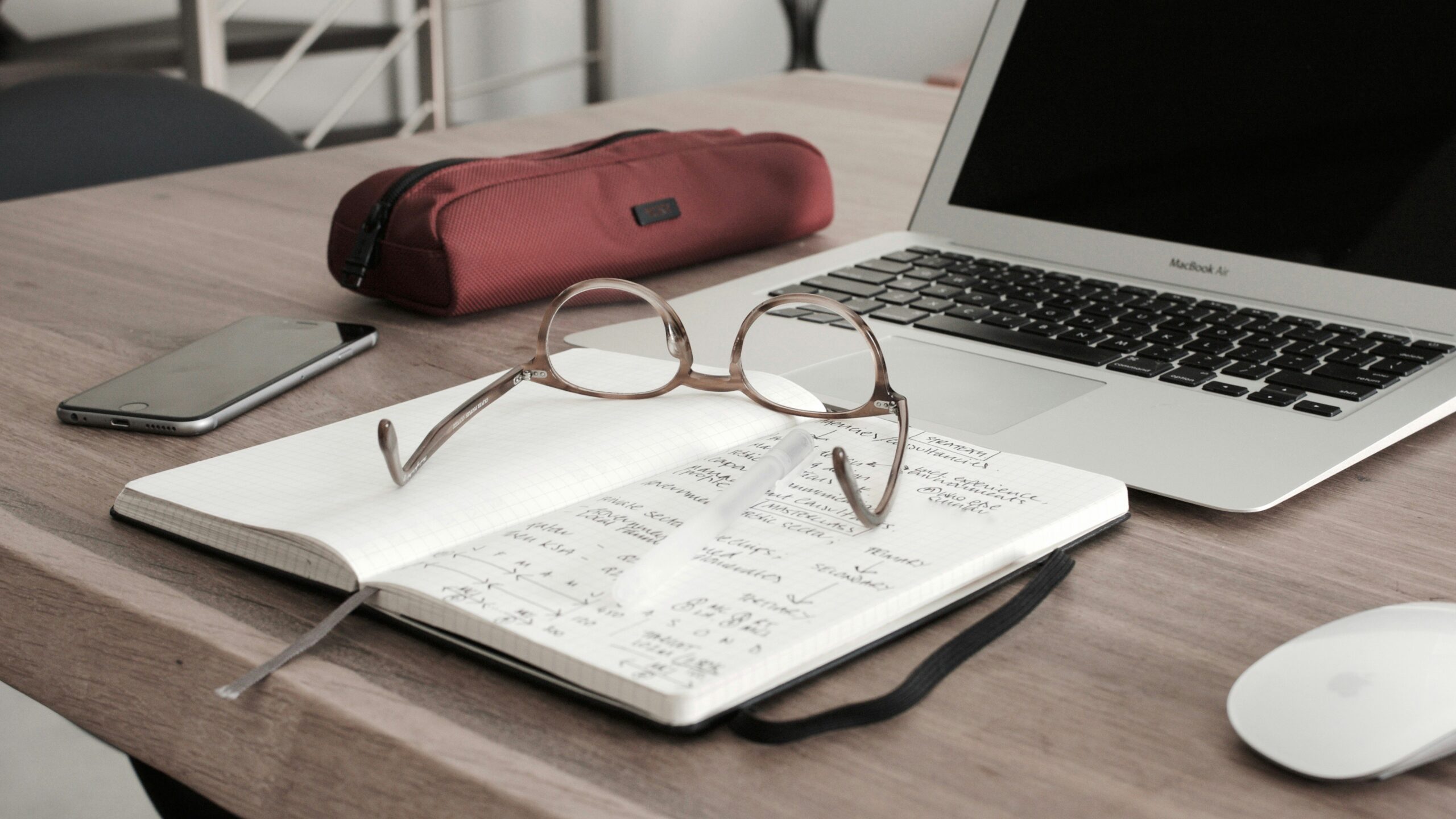 a desk with a notebook, glasses and laptop positioned on it | Speeding up Airport Authority’s financial reporting with insightsoftware