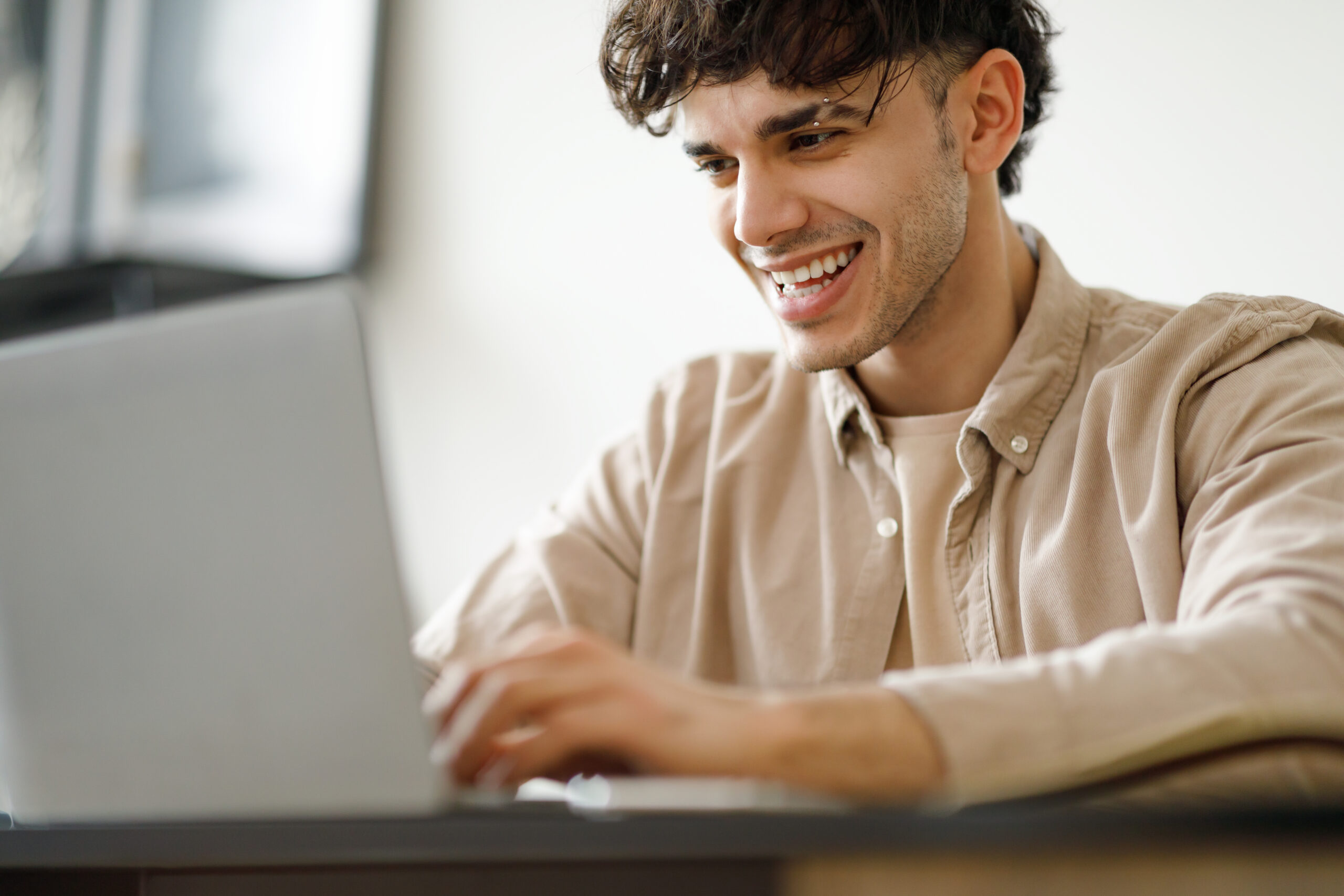 photo of a young man looking at the laptop and smiling | NewRocket interface and taxonomy solutions and consulting