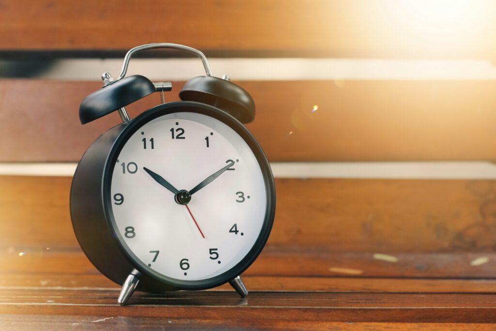 A black alarm clock resting on a brown wooden bench | Original Software testing