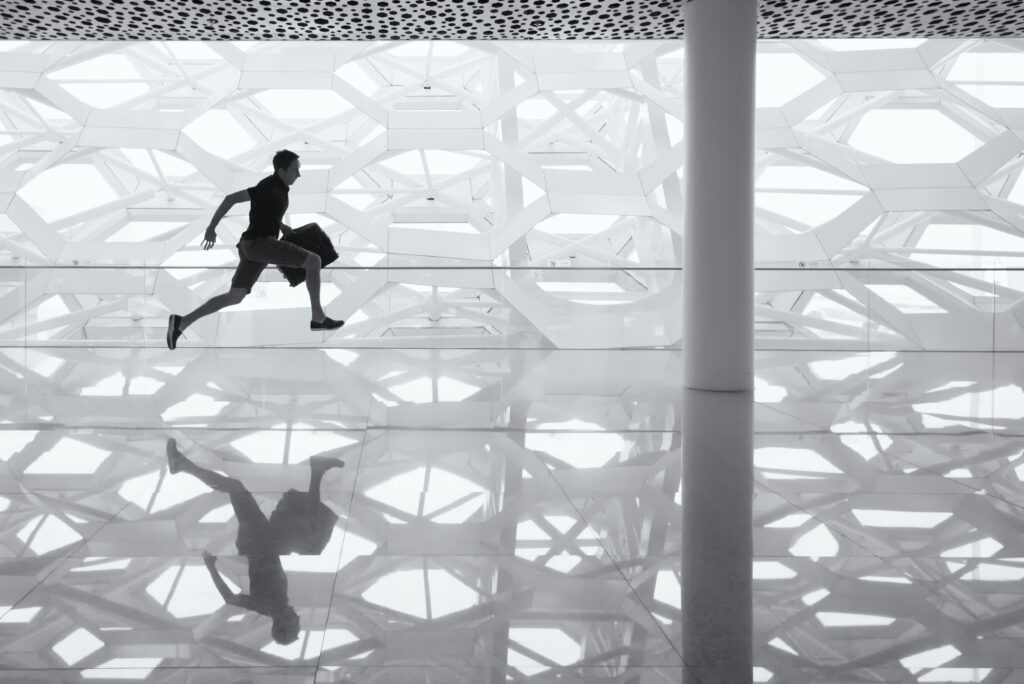 Image of a business person running with a suitcase in a large glass building | Nextworld JD Edwards Oracle