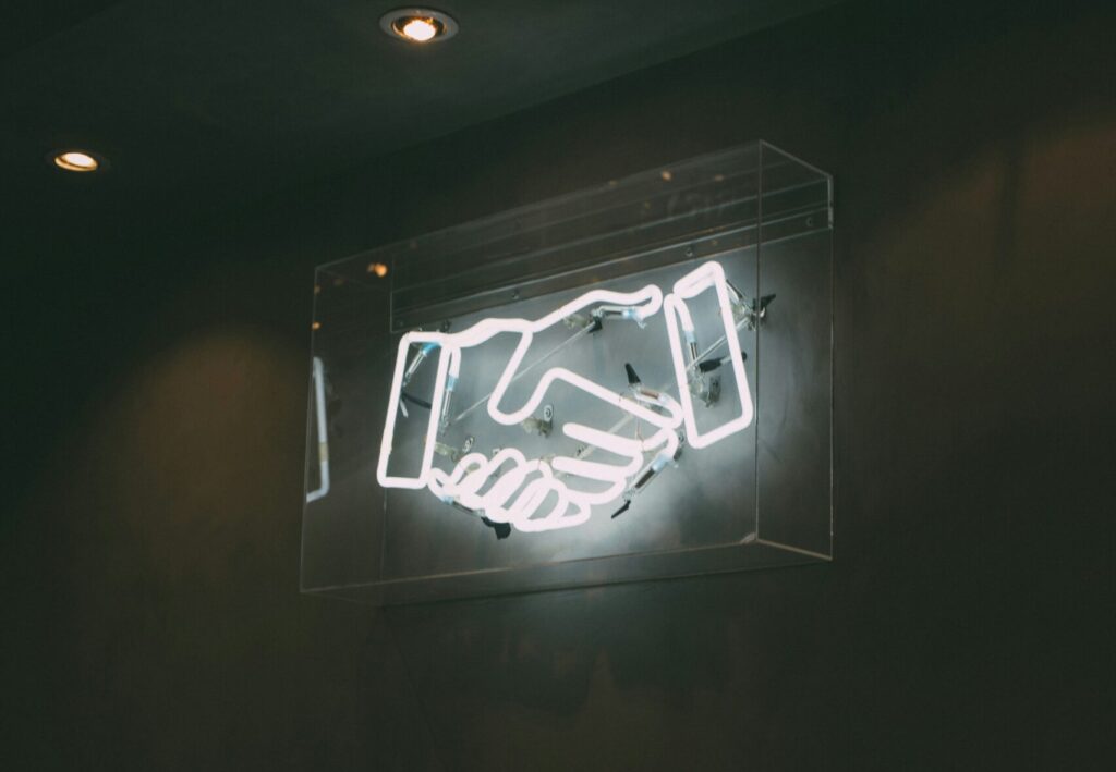 a handshake neon sign | UiPath and SAP partnership