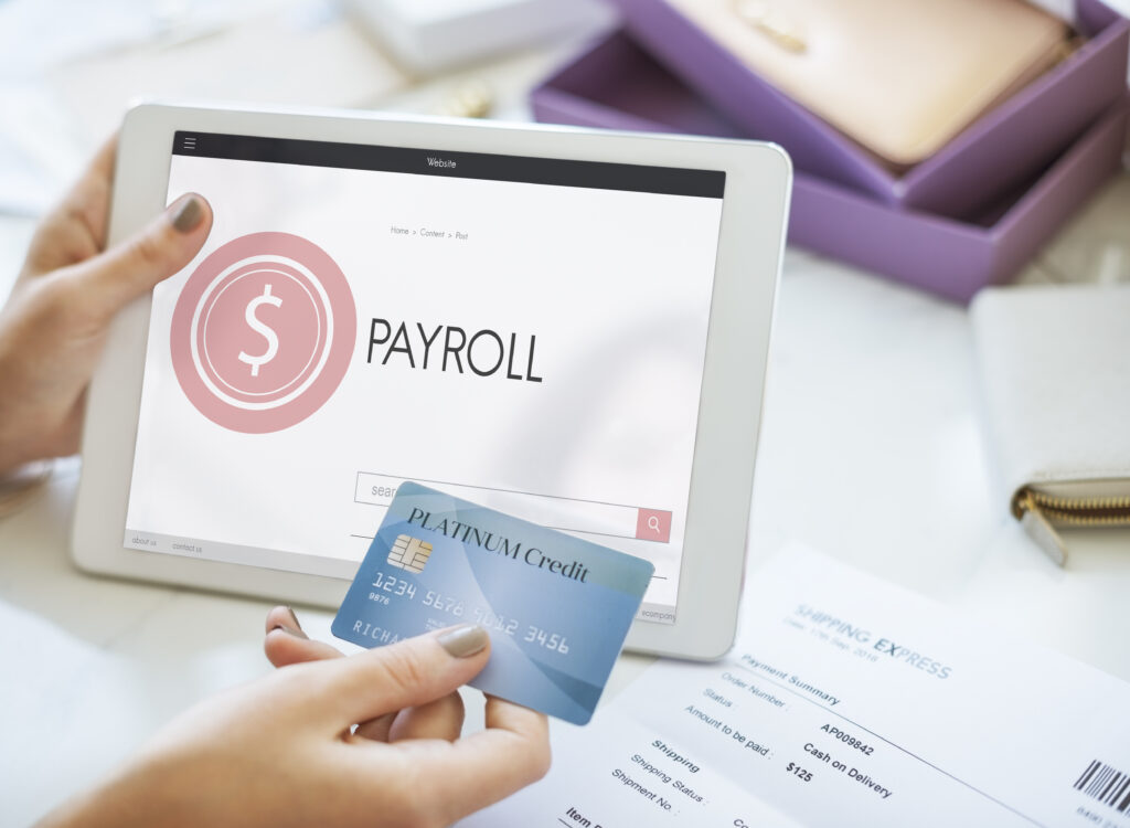 a woman holding a tablet with 'Payroll' written on it and a blue credit card | EY launches Integrated Global Payroll Solution for payroll management