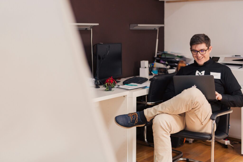 man sitting in an office with a laptop and smiling | Original Software automated testing solution