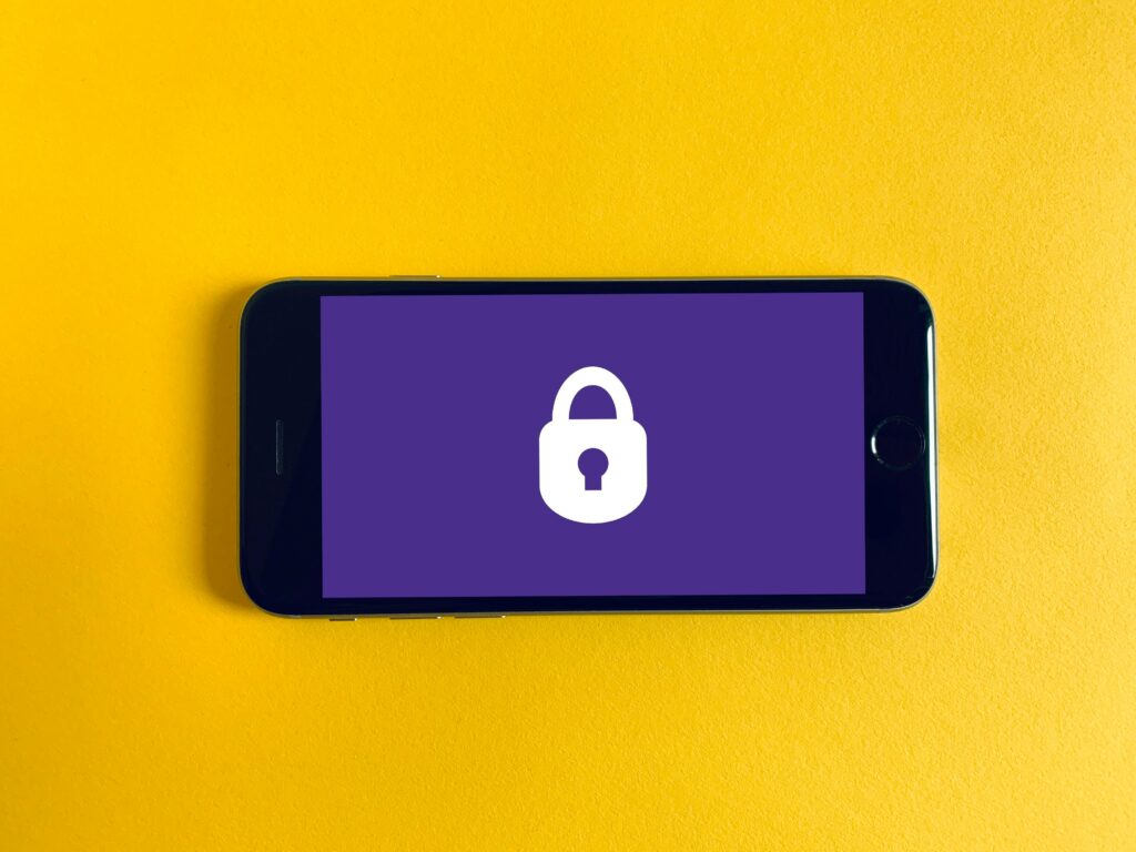 photo of a phone lying on a yellow background with a white lock sign and purple background on the screen | SUSE AI platform for privacy and security