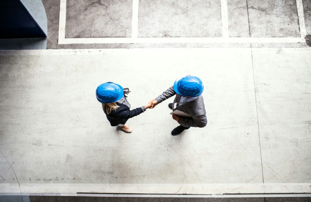 two people wearing blue hard hats having a handshake | Strategies for SAP system carveouts and M&A